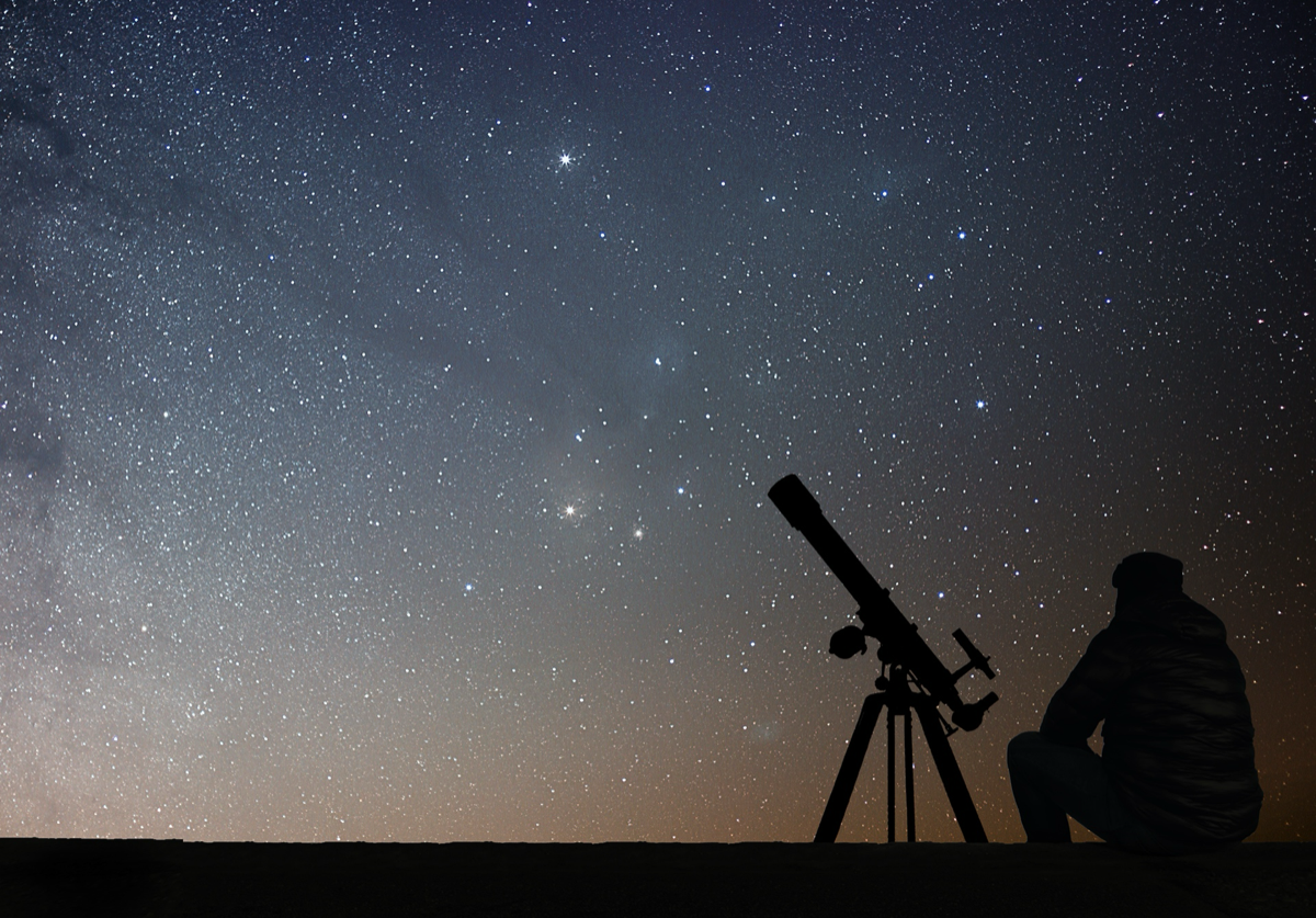 Beobachter mit Teleskop unter dem Sternenhimmel